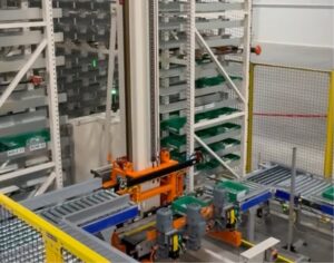 Benfits of Ultrastore Mini ASRS - ISD UltraStore Mini ASRS retrieving totes from vertical storage racks and transferring them to conveyor system at pick station